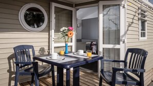 A covered outdoor seating area with a table and chairs, a vase with flowers, and a window with a view. - Charming Getaway with Garden (Tarragona)