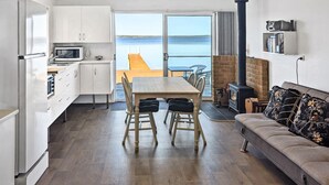 A modern kitchen with white cabinets, a dining table with chairs, a sofa, and a fireplace.
