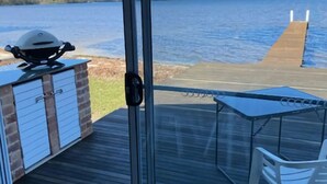 A deck with a grill, a table, and a chair.