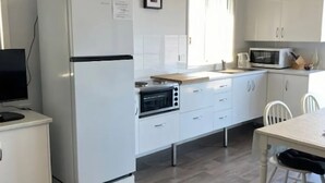 A compact kitchen with white cabinetry, a built-in oven, a microwave, and a dining area with a table and chairs.