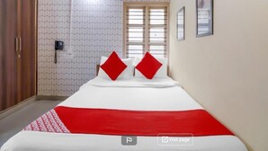 Een hotelkamer met een bed, een kledingkast, een airconditioning en een raam met zonwering.