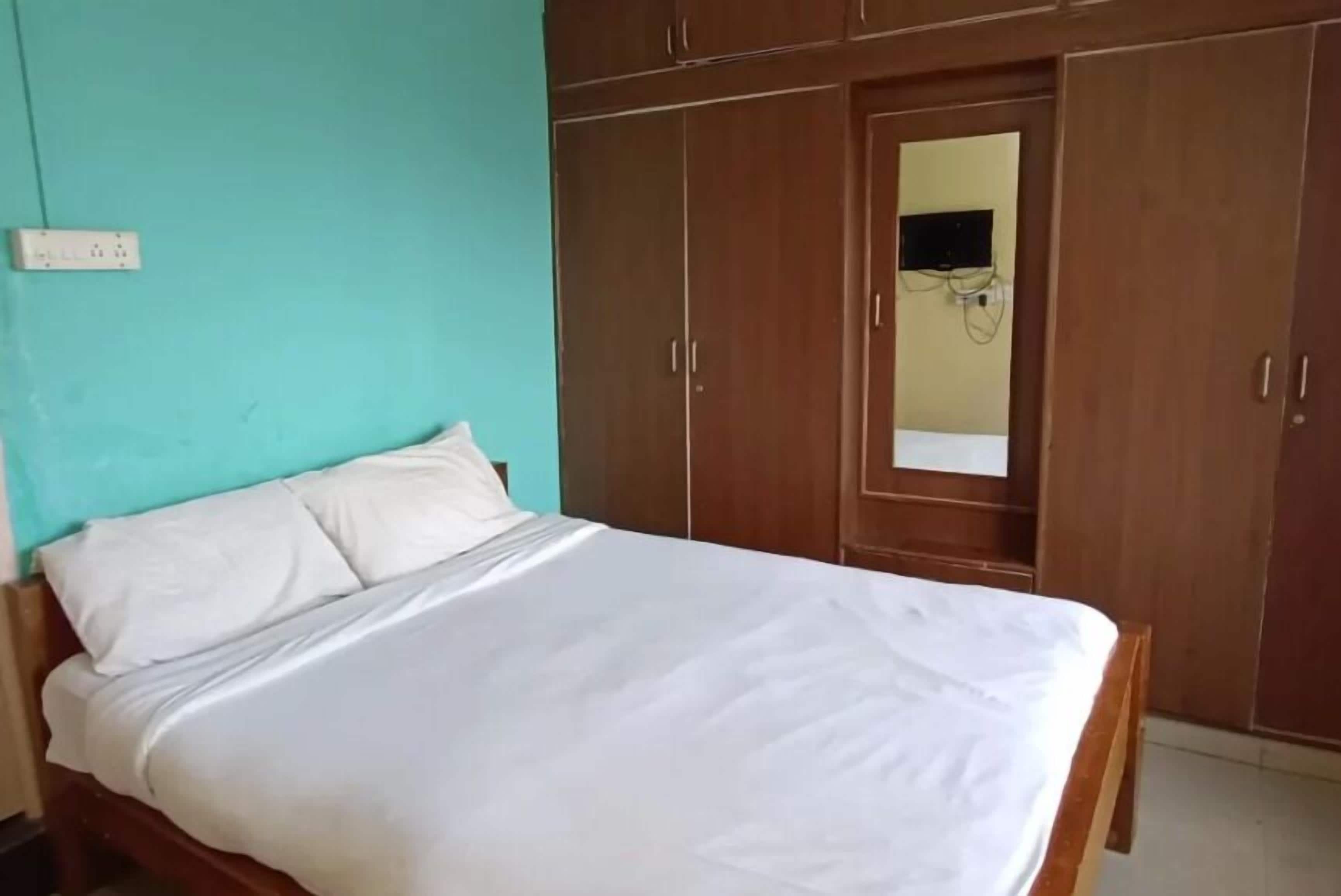 A bedroom with a bed, a wardrobe, and a mirror.