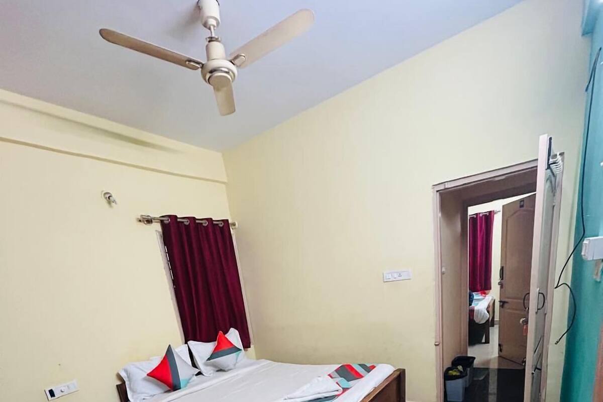 A bedroom with a bed, a ceiling fan, a door, and a tiled floor.