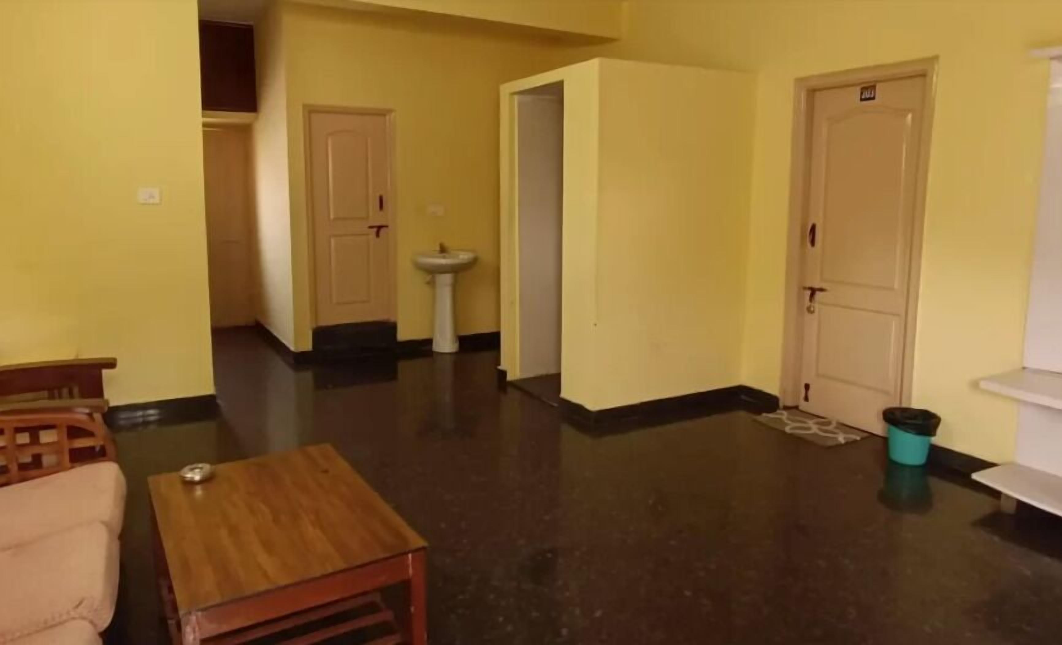 A room with a wooden table, a sofa, a sink, and a door with a handle.