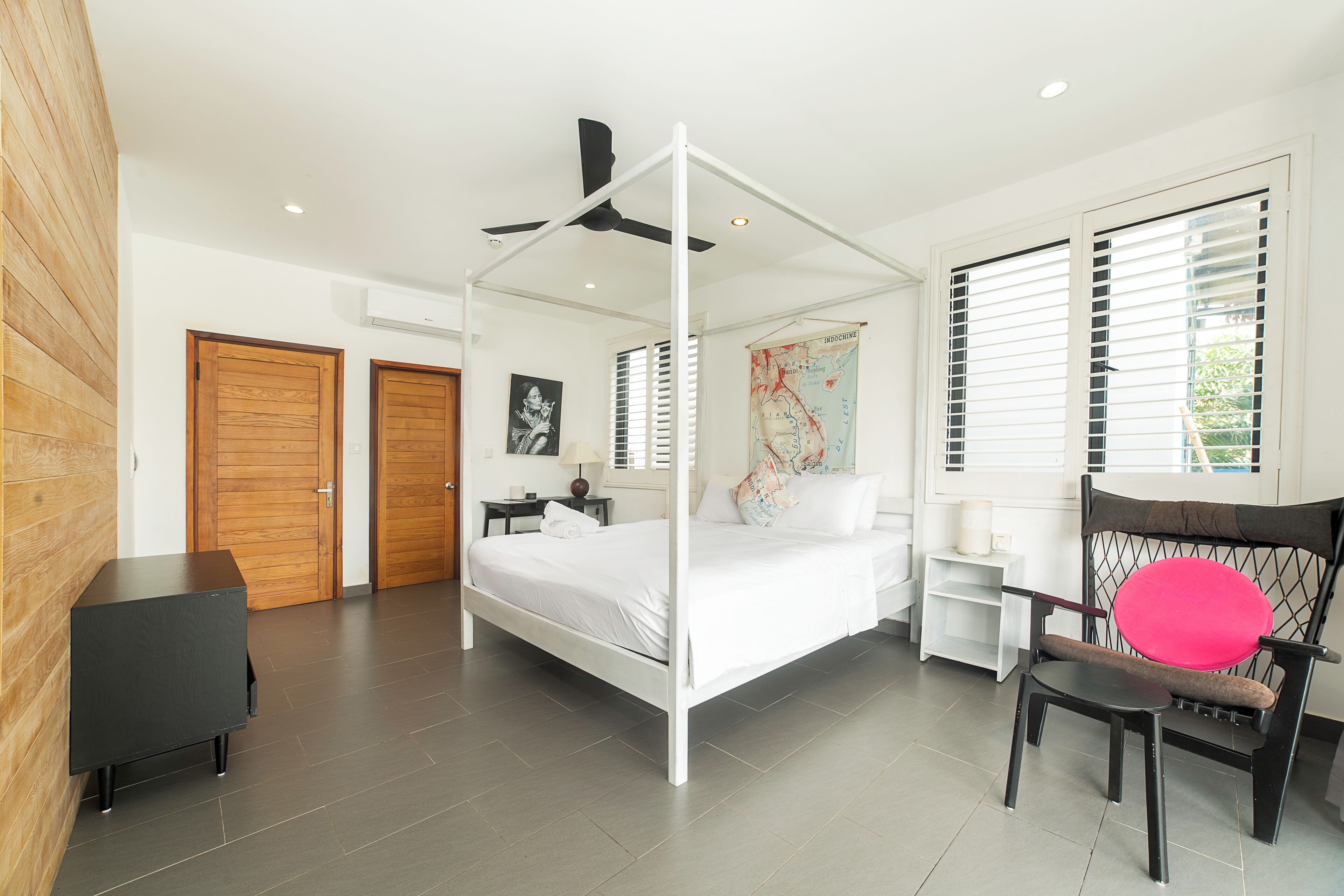 A modern bedroom with a four-poster bed, a ceiling fan, and a map on the wall.
