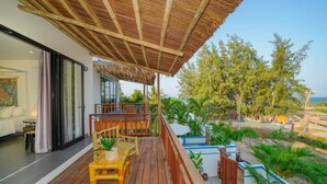 Une terrasse en bois, dotée de mobilier d’extérieur, d’un espace abrité et offrant une vue sur la végétation et le paysage environnants.