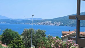 A coastal view with a clear blue sea, a distant town, and a mountain range. - Stan Julietta - With a Boka Bay View Ground Floor With a Residential Parking (Ðenovici)