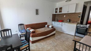 A compact living space with a sofa, dining table, chairs, a kitchenette, and a tiled floor. - Stan Julietta - With a Boka Bay View Ground Floor With a Residential Parking (Ðenovici)