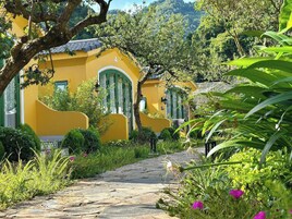 Um edifício amarelo com janelas verdes e um caminho de pedra que o leva.