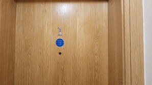 Une porte en bois avec une plaque bleue sur laquelle est écrit : « Porte coupe-feu, à garder fermée. »