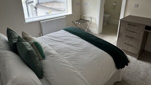 A bedroom with a bed, a radiator, a window, a drying rack, and a small wooden cabinet. - Class Stays - Room 2 (Shrewsbury)