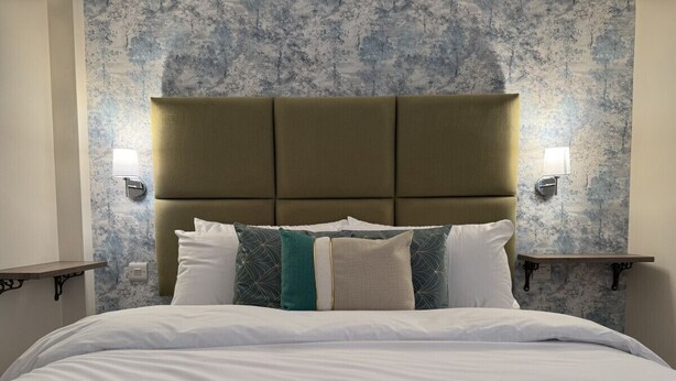 A hotel room with a large bed, a headboard, and two wall-mounted lamps. - Class Stays - Room 5 (Shrewsbury)