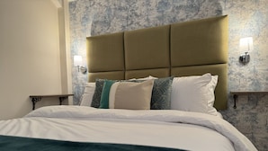 A bed with a headboard, multiple pillows, and a blanket. - Class Stays - Room 5 (Shrewsbury)