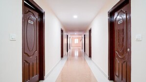 Un long couloir étroit, avec des portes en bois de chaque côté, numérotées 105 et 106, qui mène à une pièce au fond.