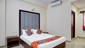 Une chambre d’hôtel avec un grand lit, une table de chevet, un appareil de climatisation et une porte avec une fenêtre.