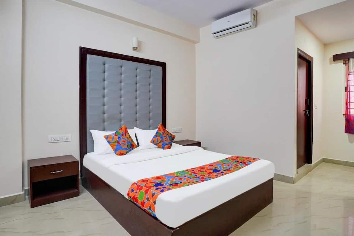 Quarto de hotel com uma cama grande, uma mesa de cabeceira, um aparelho de ar condicionado e uma porta com janela.