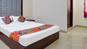 Un lit bien fait, avec un matelas blanc et une couvre-lit aux motifs géométriques colorés.