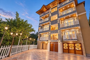 A multi-story hotel with balconies, a white picket fence, and a paved driveway.