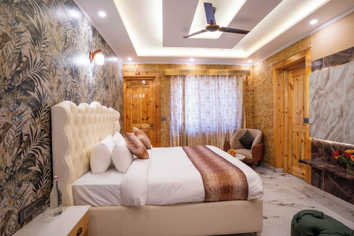 Un dormitorio con una cama grande, una puerta de madera, una silla verde y una pared de mármol.