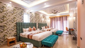 Ein modernes Schlafzimmer mit zwei großen Betten, einem kleinen Tisch mit Früchten und einer Sitzecke.