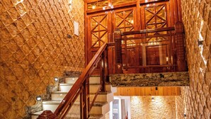 Eine Holztreppe mit einer Steinsäule und einem Holengeländer.