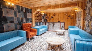 Ein Zimmer mit blauen Sofas, einem roten Sessel und einem gemusterten Boden.