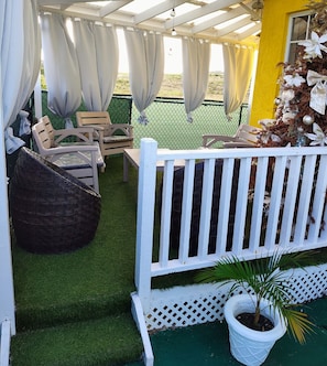 A covered patio area with chairs and a white fence.