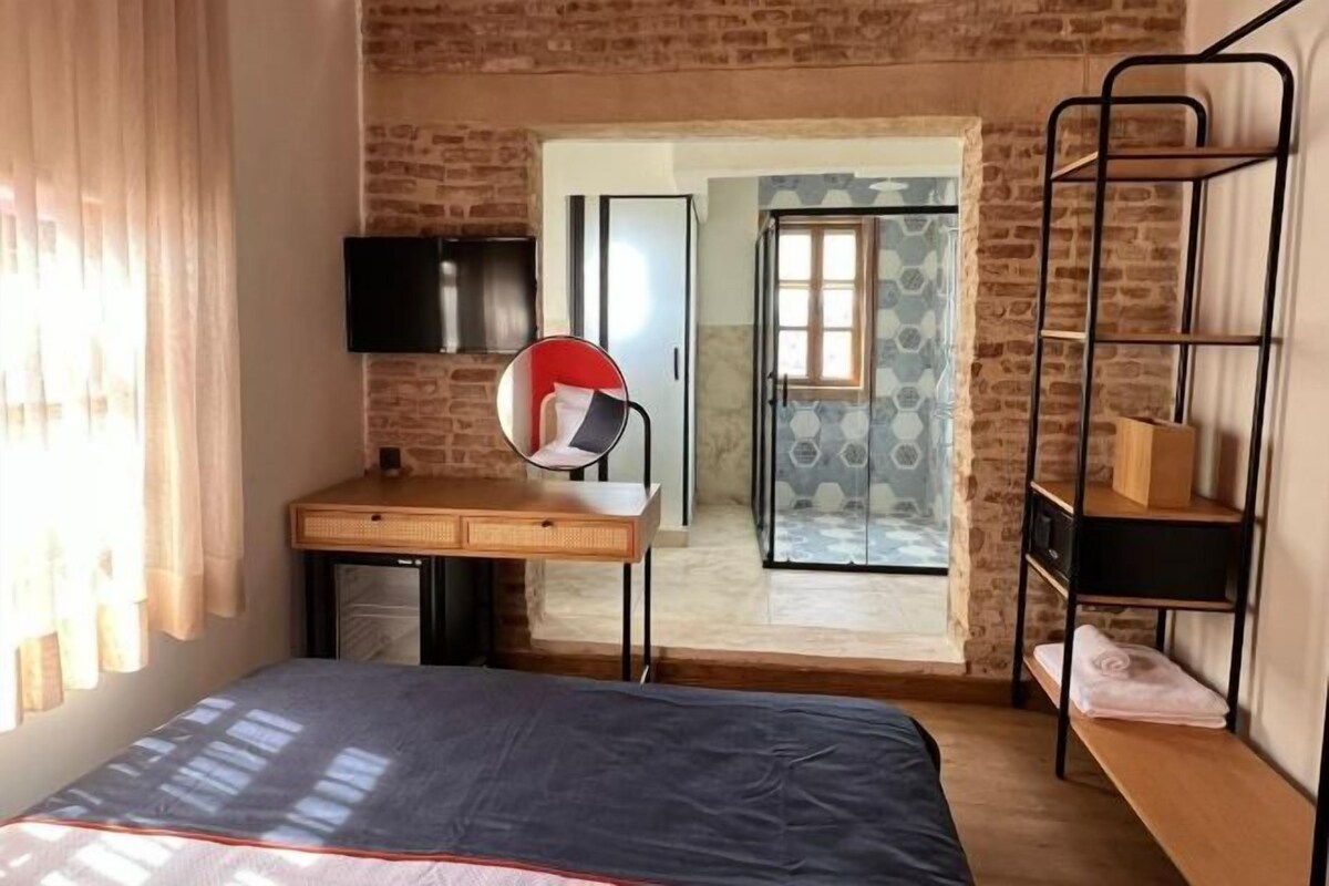 Ein kleines Schlafzimmer mit einem Bett, einem Schreibtisch, einem Fernseher und einem Etagenbett.