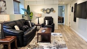 A living room with a black leather sofa, a wooden coffee table, and a patterned rug.