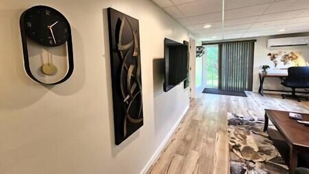 A modern interior with a clock, abstract art, a flat-screen TV, and a dining area with a view.