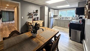 A modern kitchen with a dining area, featuring a wooden table, chairs, and a kitchen island with a sink and appliances.