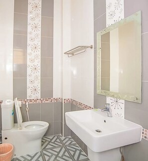 A bathroom with a toilet, sink, and mirror. - Klang mueang villa (Uthai Thani)