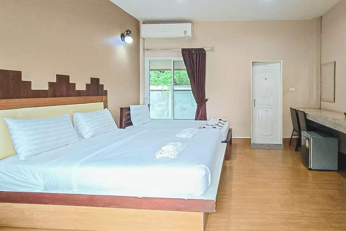 A hotel room with a large bed, a desk, a wardrobe, and a window with curtains.