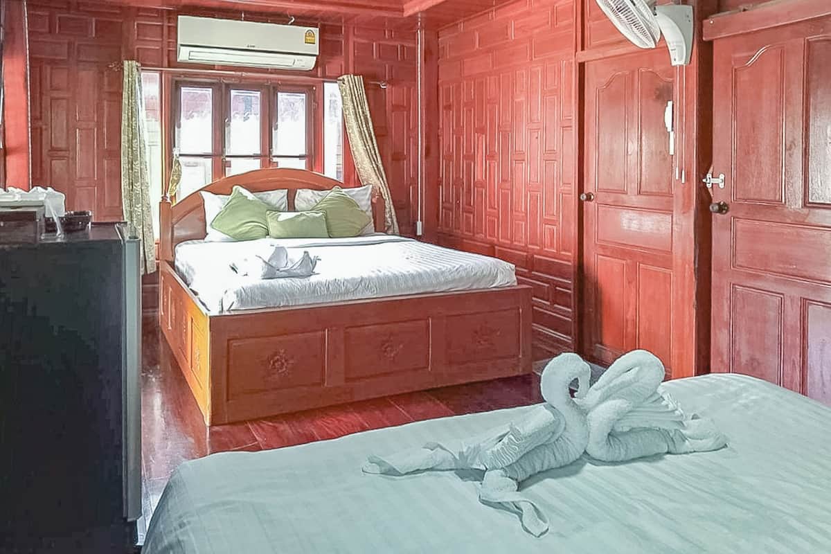 A room with a wooden bed, a bedside table, a wardrobe, and a window with curtains.