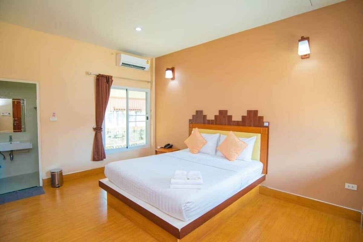 A hotel room with a wooden bed, a bathroom with a sink, and a window with curtains.