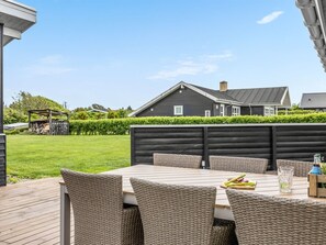 Une terrasse extérieure avec des meubles en osier, une table et un verre d’eau.