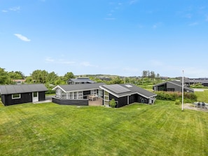 A modern residential area with multiple houses, a well-maintained lawn, and a clear sky.