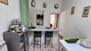 Eine kompakte Küche mit Kochinsel, zwei Barhocker, einem Esstisch mit Laptop und einem Musterboden.