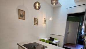 Eine moderne Küche mit einer zentralen Kochinsel, Pendelleuchten und gerahmten Pflanzenbildern an der Wand.