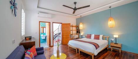 Ein modernes Schlafzimmer mit Bett, Sofa, einem kleinen Tisch und Deckenventilator.