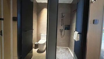 Un baño moderno con mampara de vidrio, inodoro, zona de ducha y un perchero para toallas.