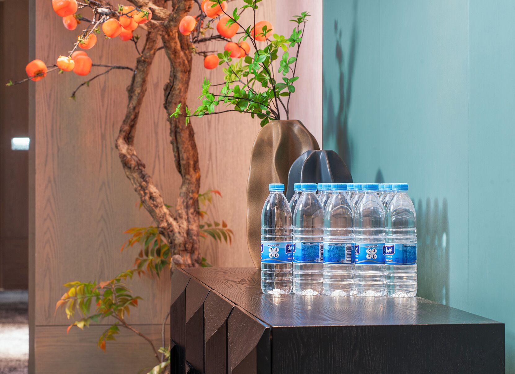 A wooden table with water bottles and a vase with a plant.