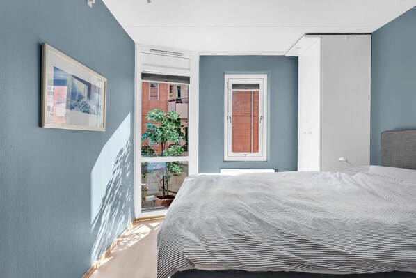 Un dormitorio con una cama, una puerta, una ventana y un cuadro en la pared.