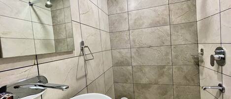A bathroom with a white sink, a mirror, a shower, and tiled walls.