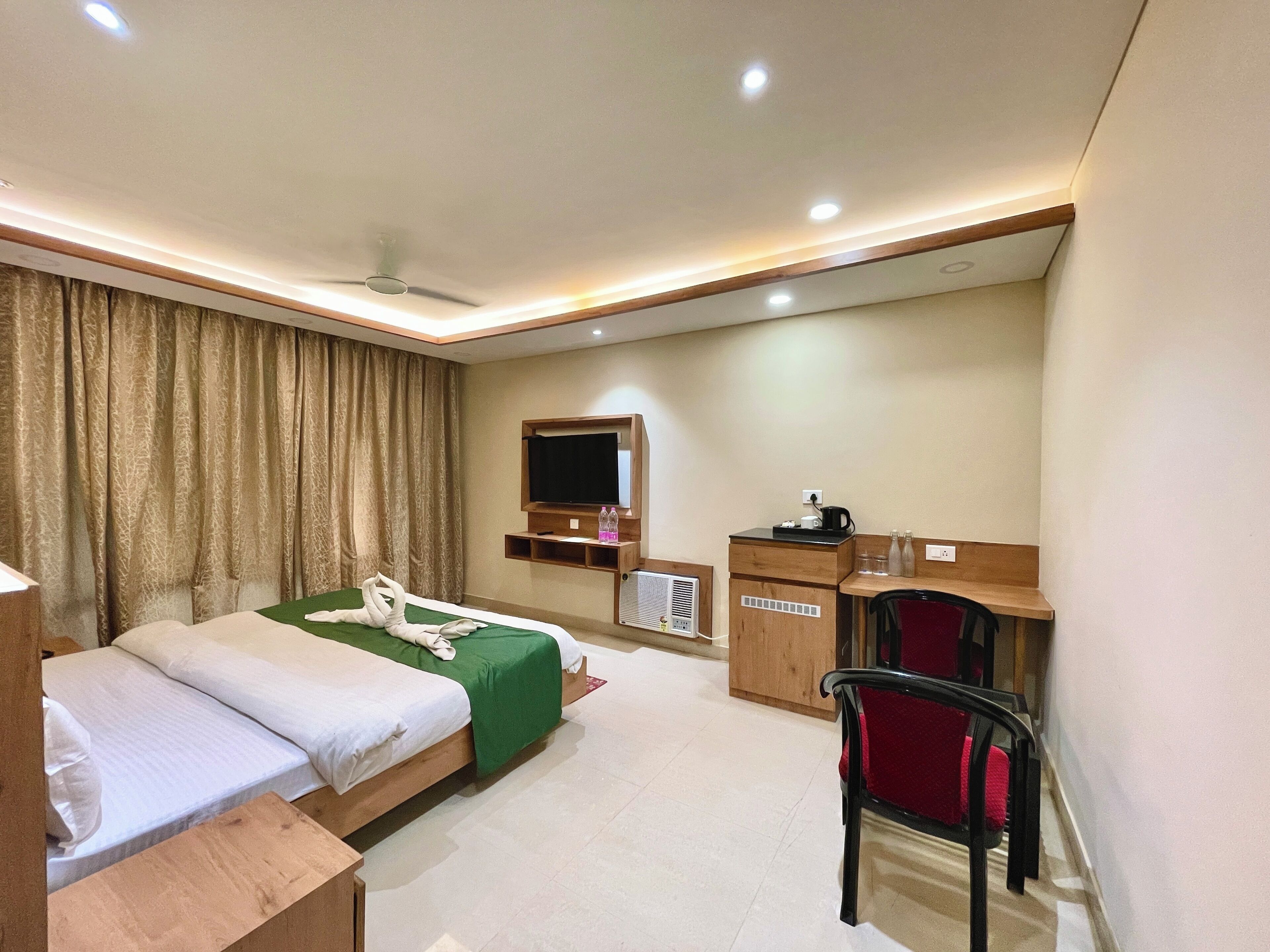 A hotel room with two beds, a desk, a chair, a TV, and a wardrobe.