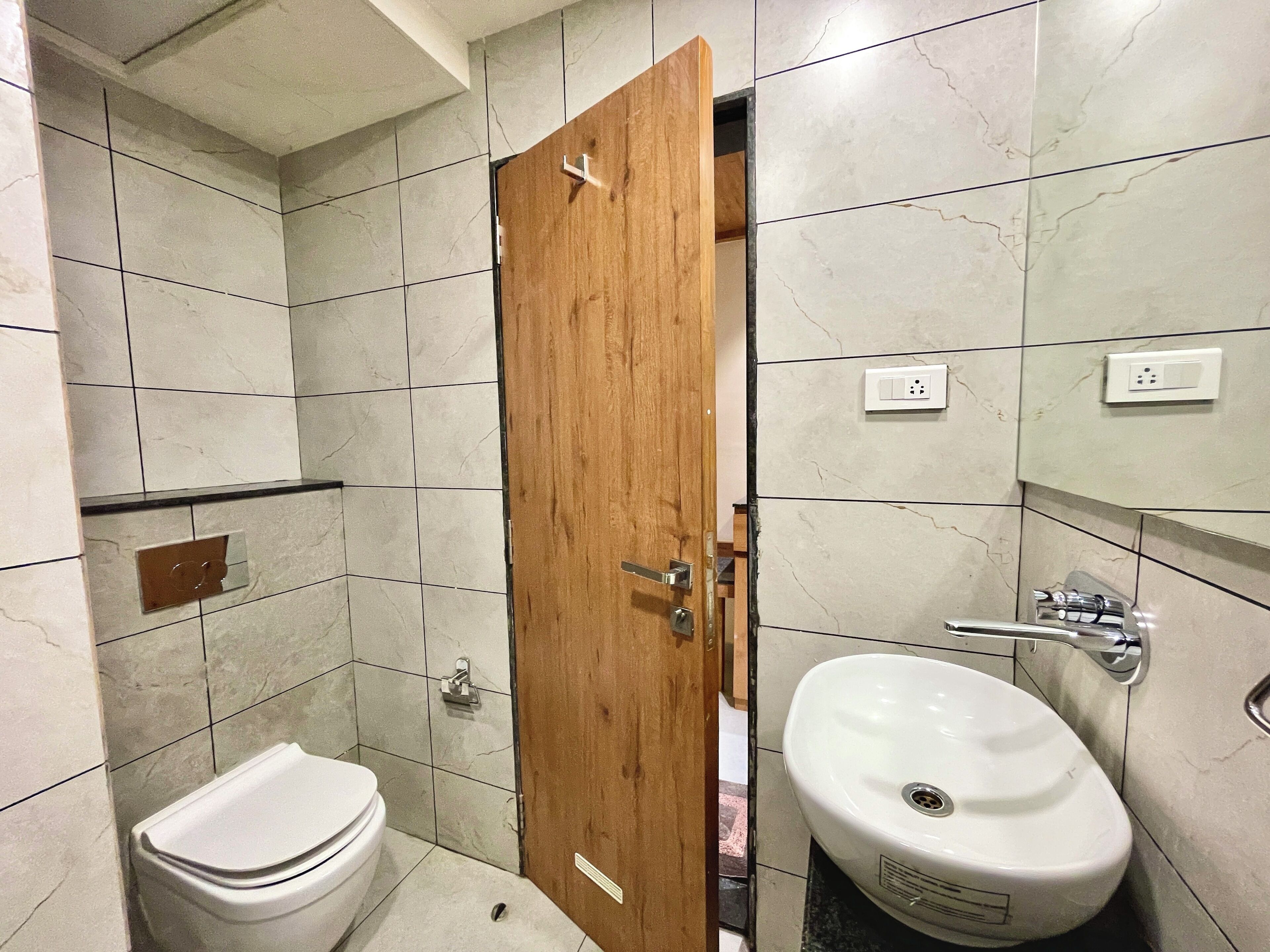 Baño con inodoro, lavabo y puerta de madera.
