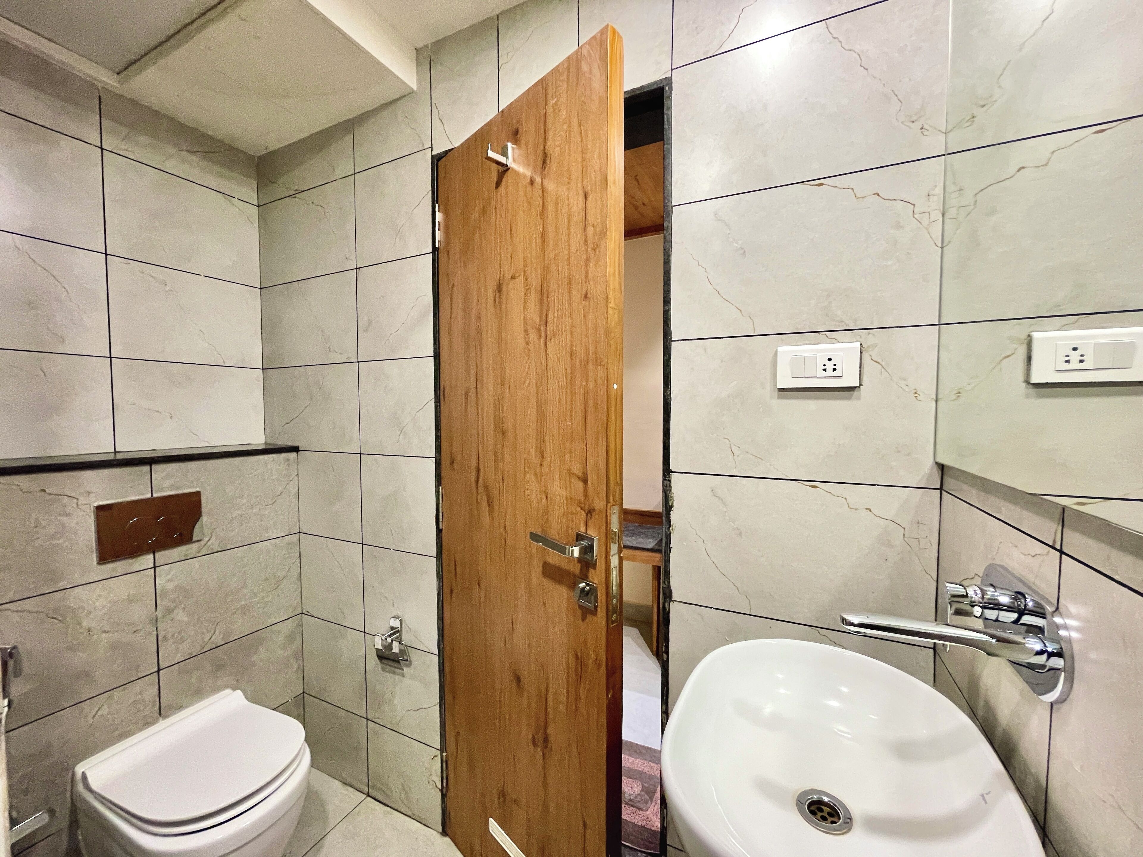Un baño con inodoro, lavamanos y puerta de madera.