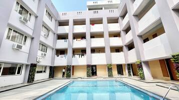 Guests can enjoy a refreshing swim in the central courtyard pool surrounded by a deck and lush greenery.