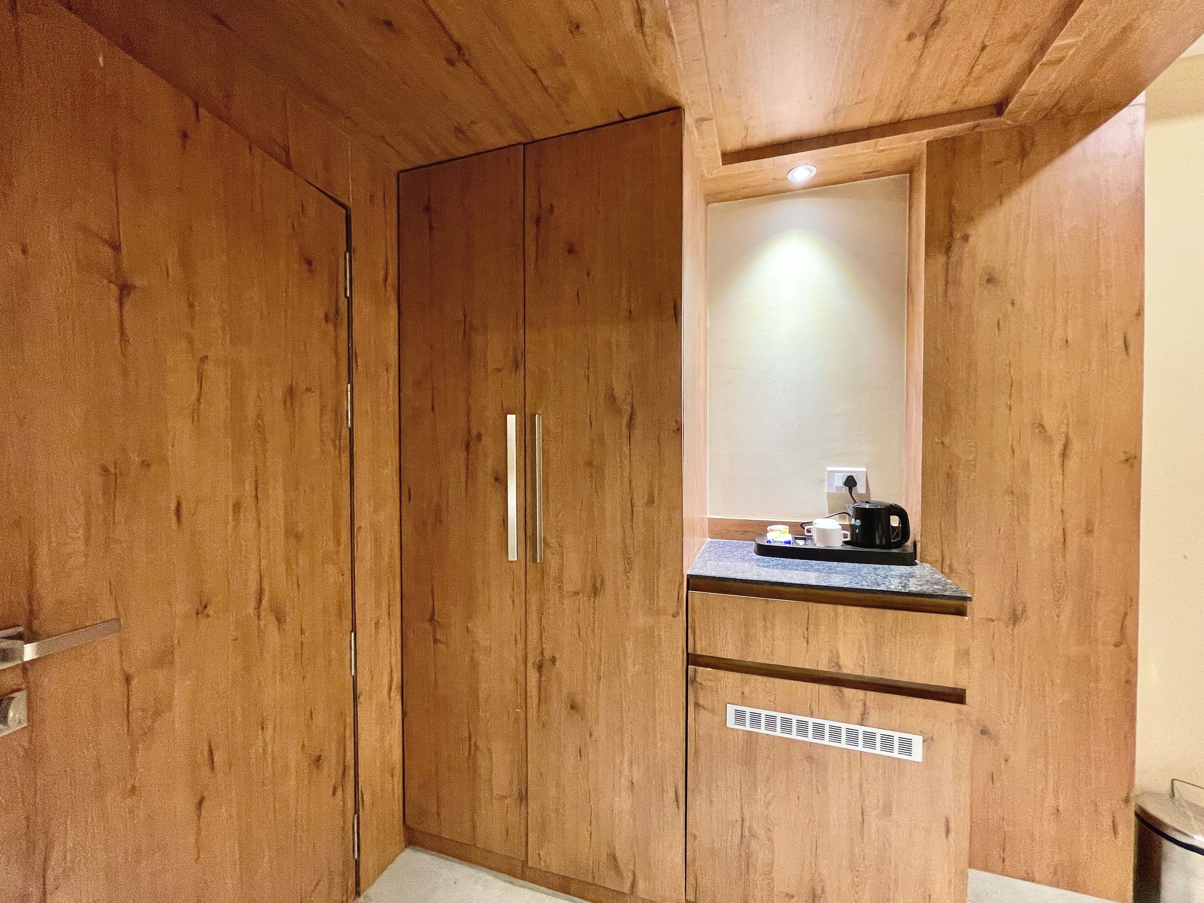 Une pièce en bois avec une grande armoire, un petit miroir et un plan de travail sur lequel se trouve une machine à café.