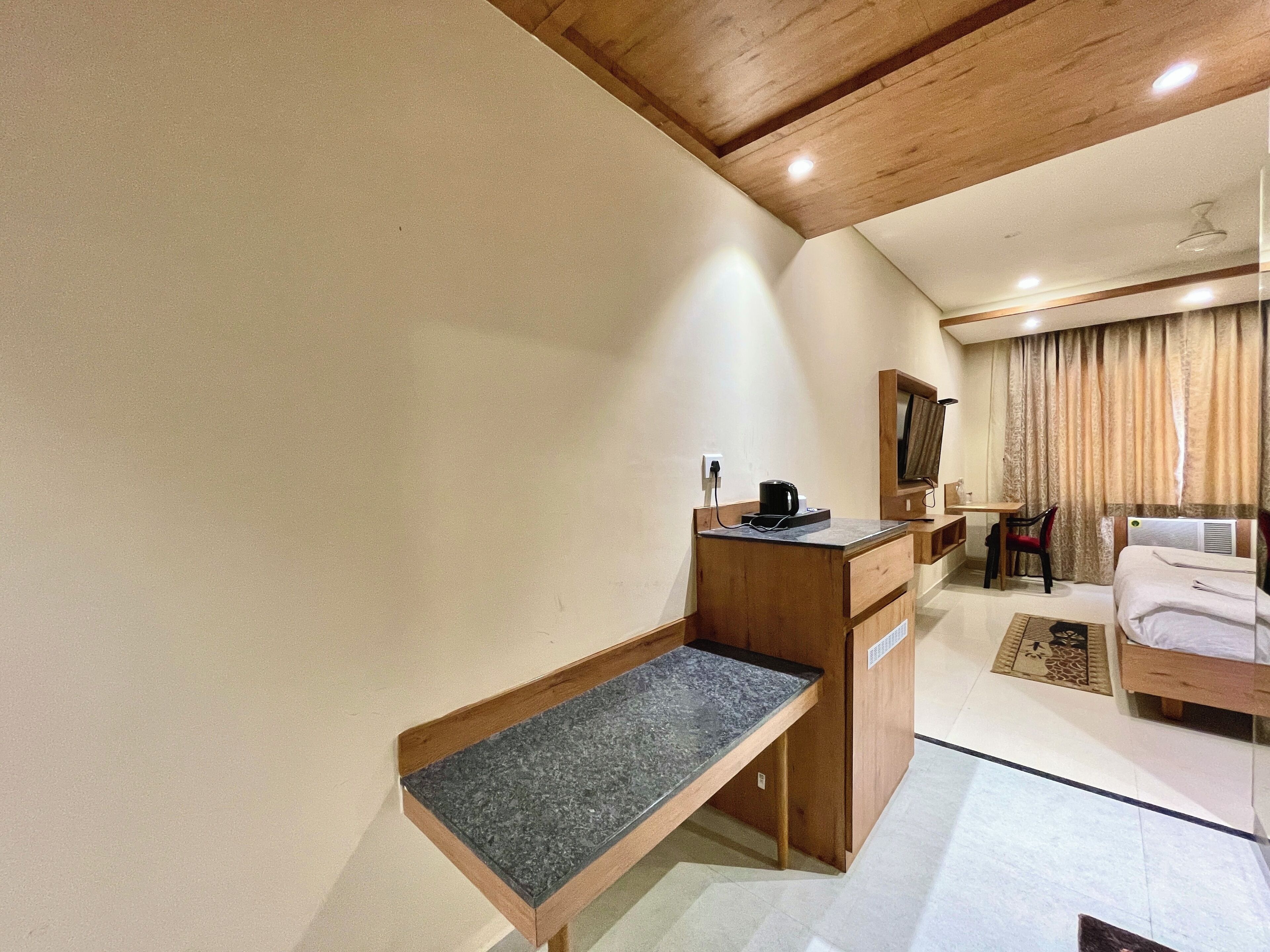 A hotel room with a wooden desk, a bed, a chair, and a TV.
